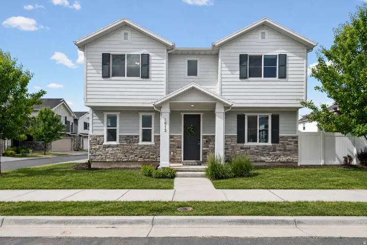 Two-story residence featuring light gray siding and a stone-clad lower facade