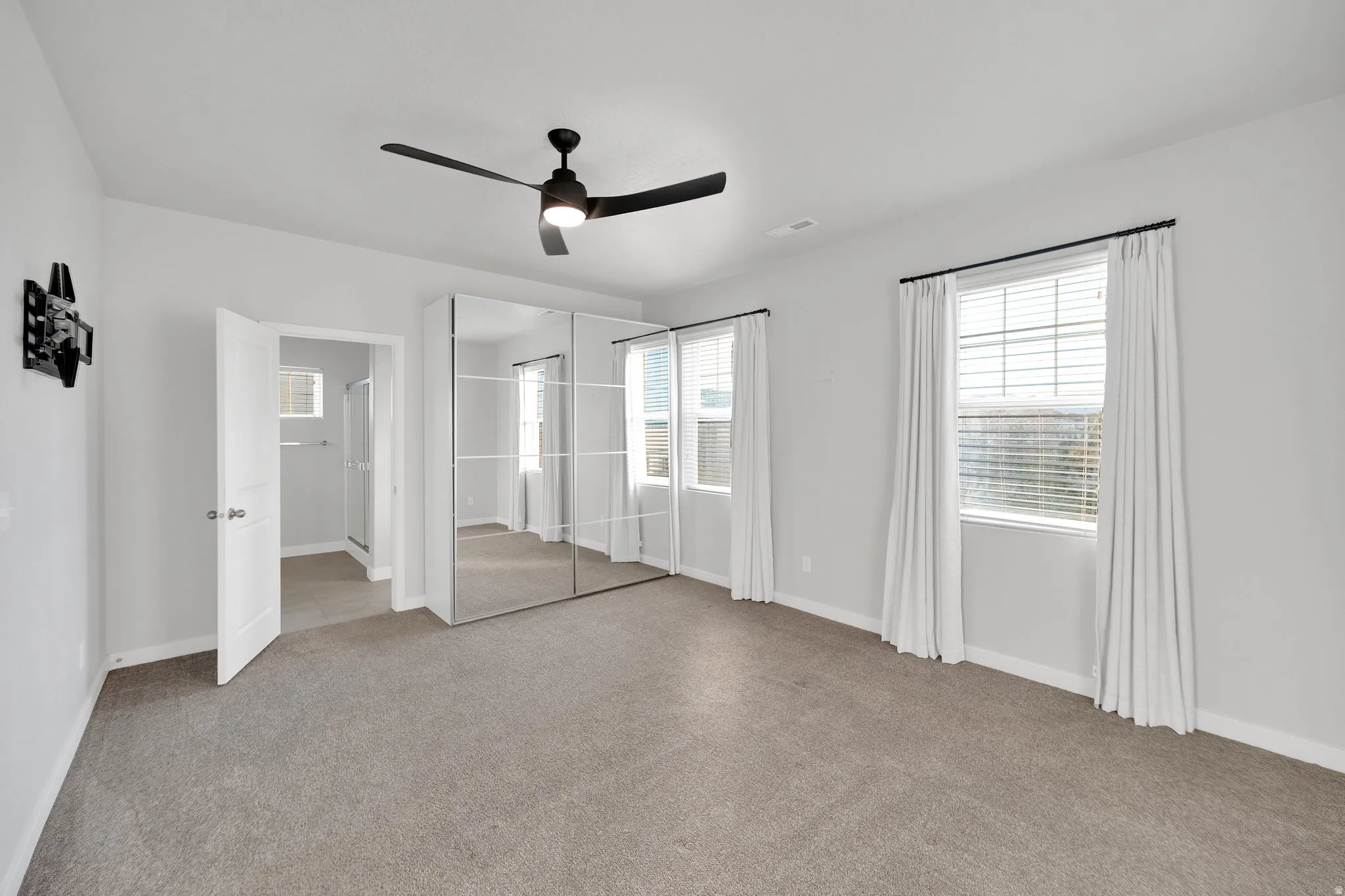 Carpeted bedroom with a dark-toned ceiling fan and light gray walls