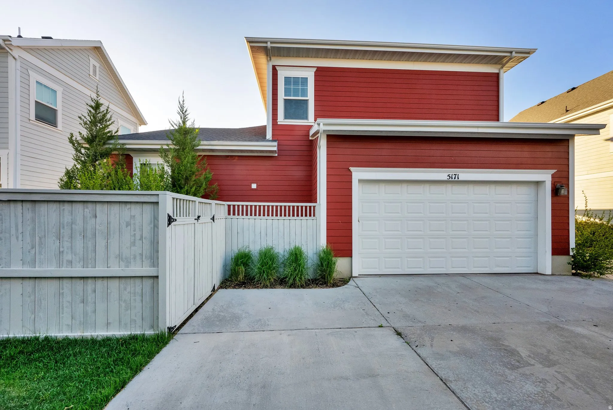 Red siding exterior featuring a white paneled garage door and a concrete driveway