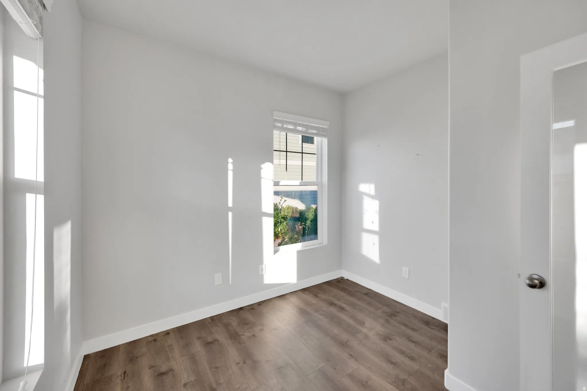 Room featuring wood-finish flooring, white baseboards, and neutral wall paint