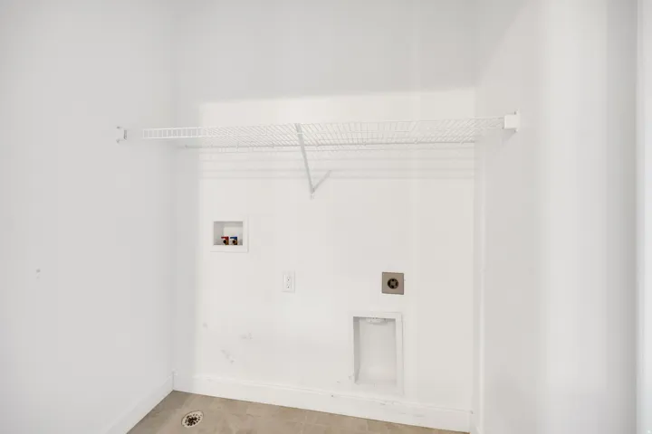 Utility room featuring a wire storage shelf, laundry hookups, and light-toned floor tiling