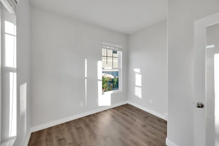 Room featuring wood-finish flooring, white baseboards, and neutral wall paint
