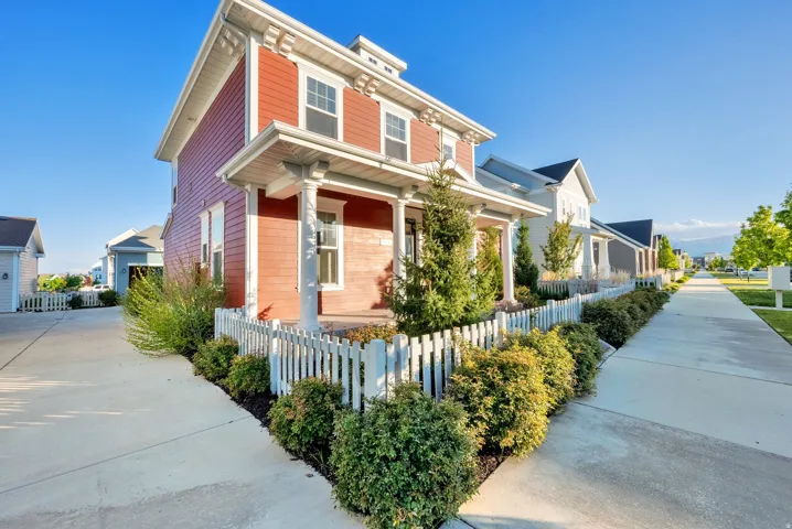 Red siding exterior with white trim details and a covered front porch featuring two columns