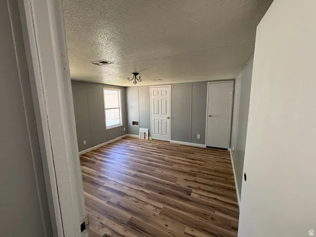 Spacious room featuring wood-finish flooring, light grey paneled walls, and a white ceiling