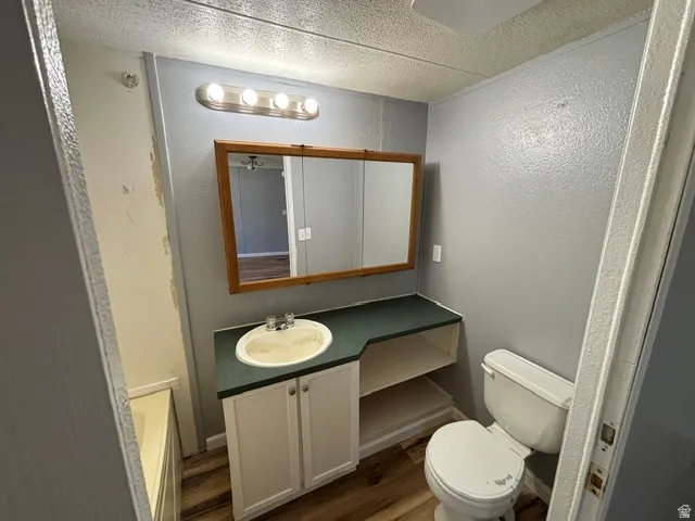 Bathroom featuring a white vanity with two cabinet doors, an integrated sink, a dark countertop, and a framed mirror