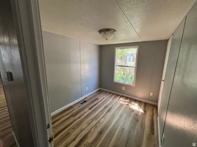 Interior room with wood-finish flooring and light gray paneled walls
