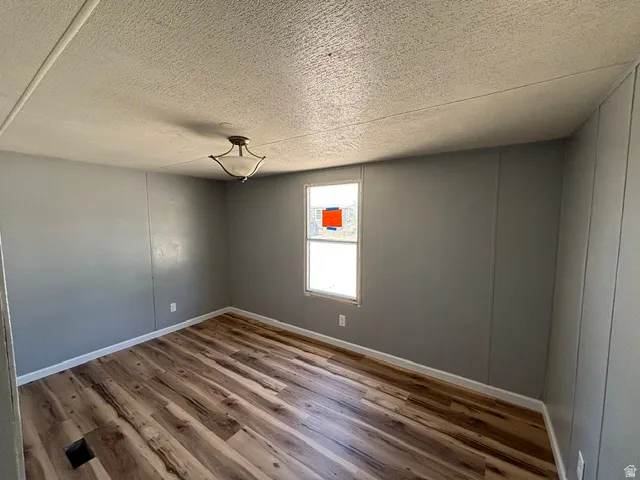 Interior space featuring wood-finish flooring, gray walls, white baseboards, and a single window