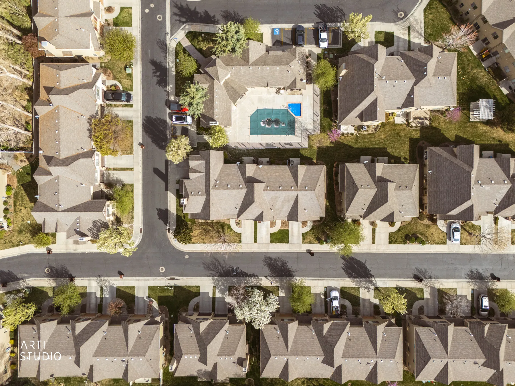 Aerial view of a residential community featuring a central swimming pool with water features, surrounded by multiple residential structures