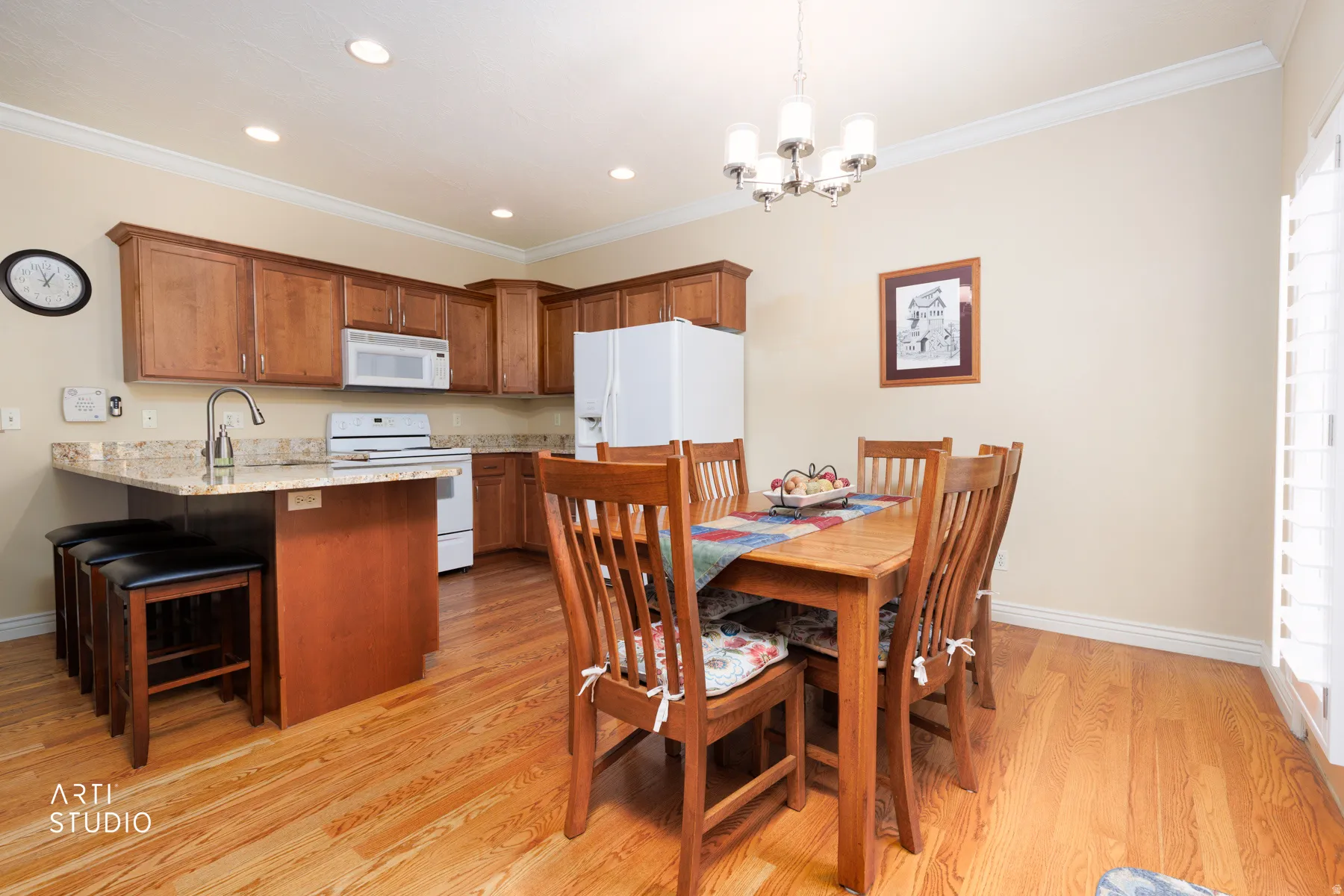 Open-concept kitchen and dining area featuring wood-finish flooring, recessed lighting, and crown molding
