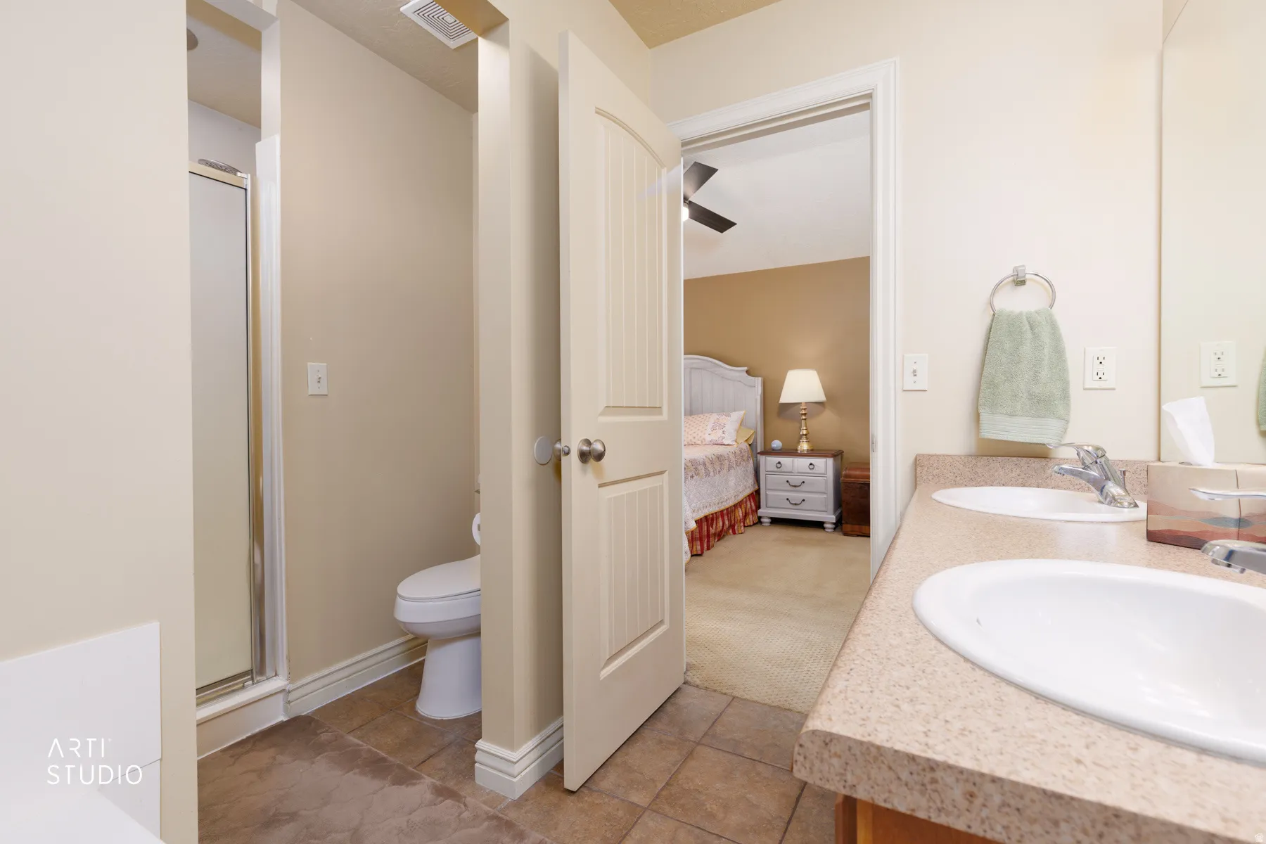 Bathroom featuring a dual vanity with light-toned countertops, a shower with a glass enclosure, a toilet, and tiled flooring