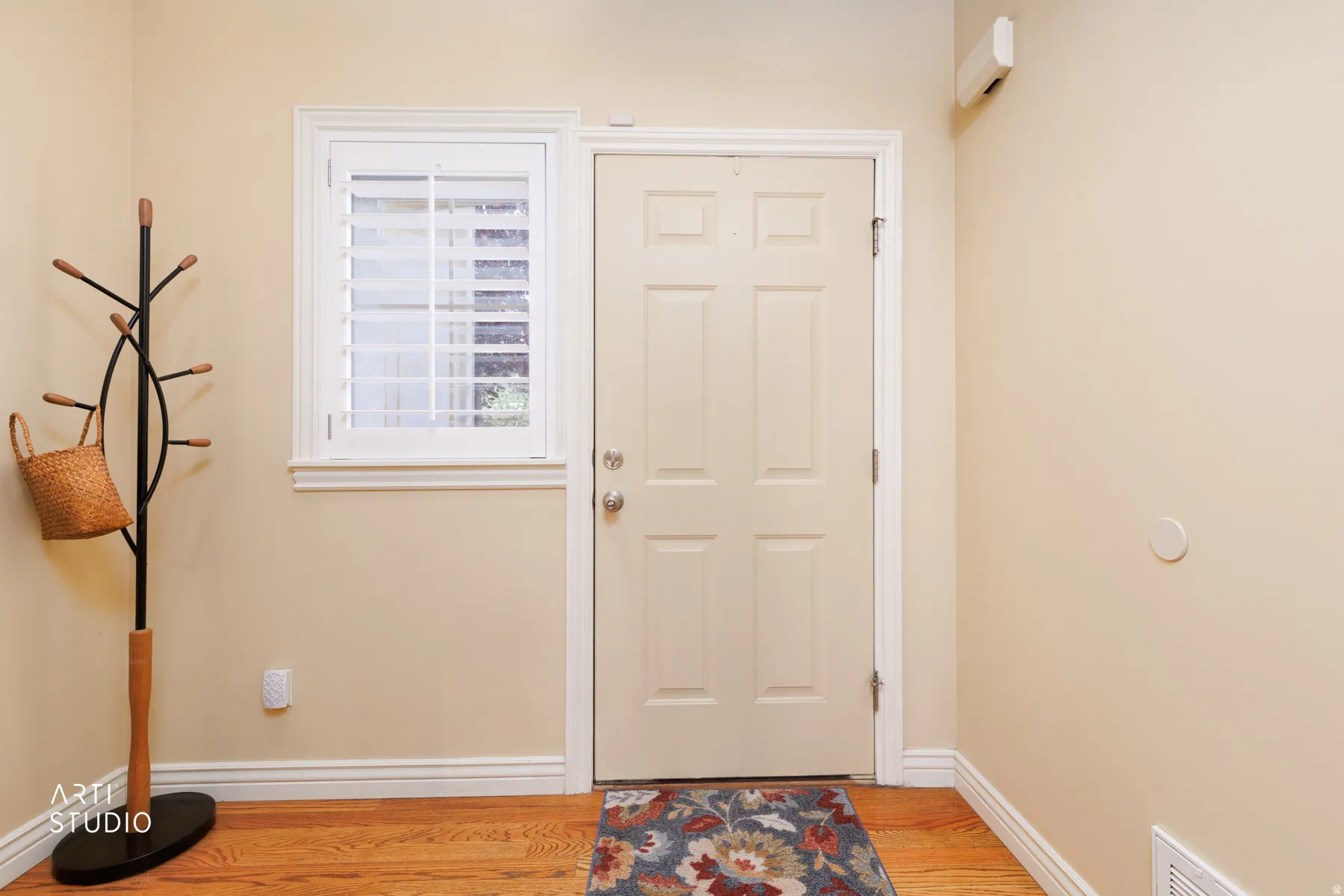 Entryway featuring a paneled door, wood-finish flooring, and a window with plantation shutters