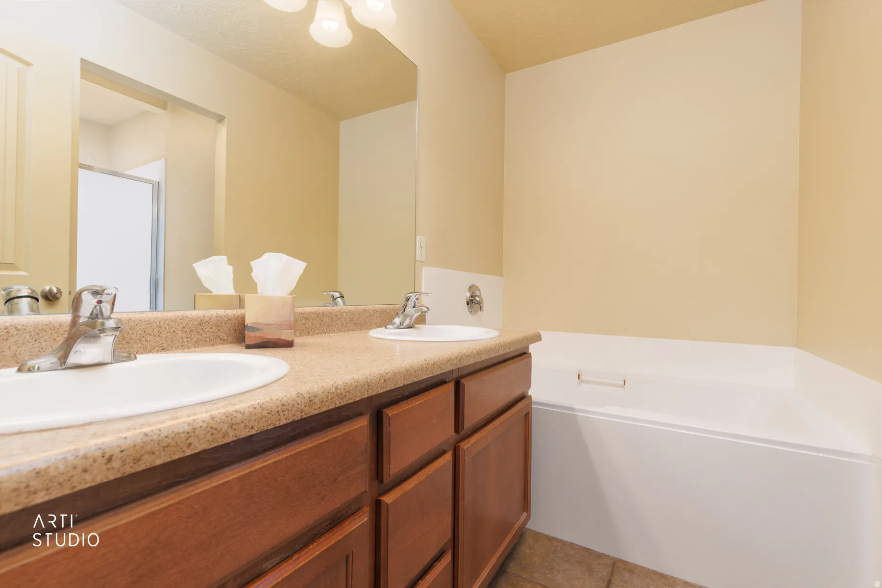 Bathroom featuring a dual-sink vanity with a speckled countertop, undermount sinks, and a built-in tub