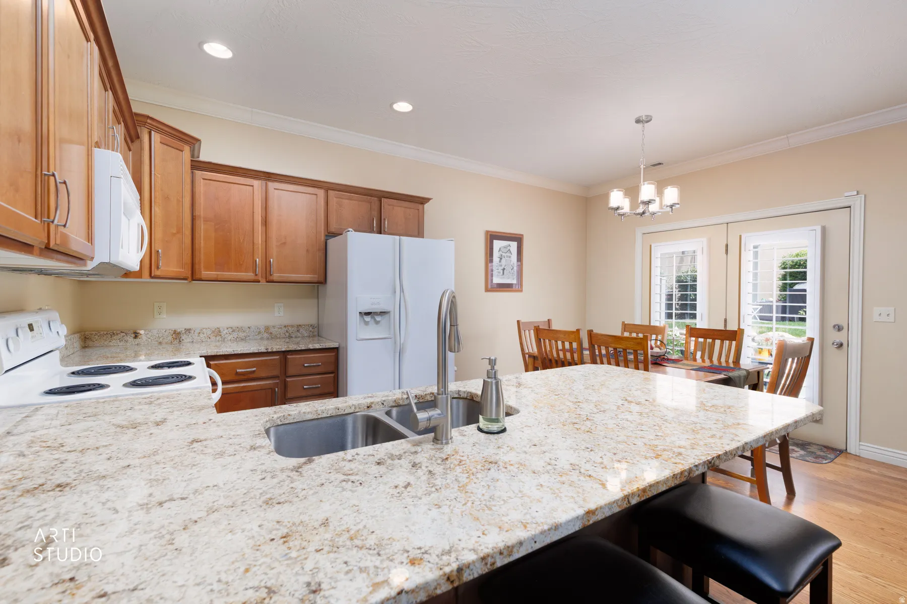 Kitchen island with a stainless steel undermount sink, granite countertop, recessed lighting, and wood-finish flooring