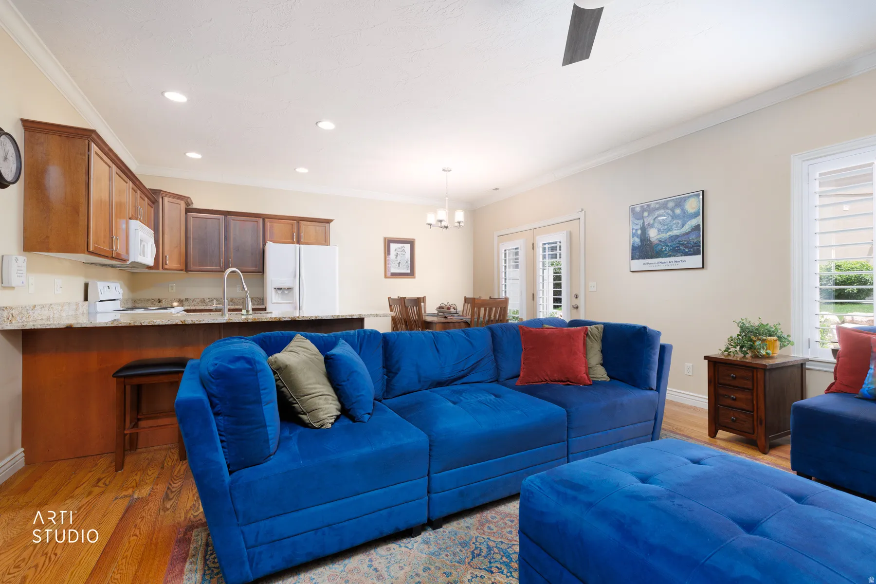 Open-concept living area featuring wood-finish flooring, recessed lighting, and crown molding