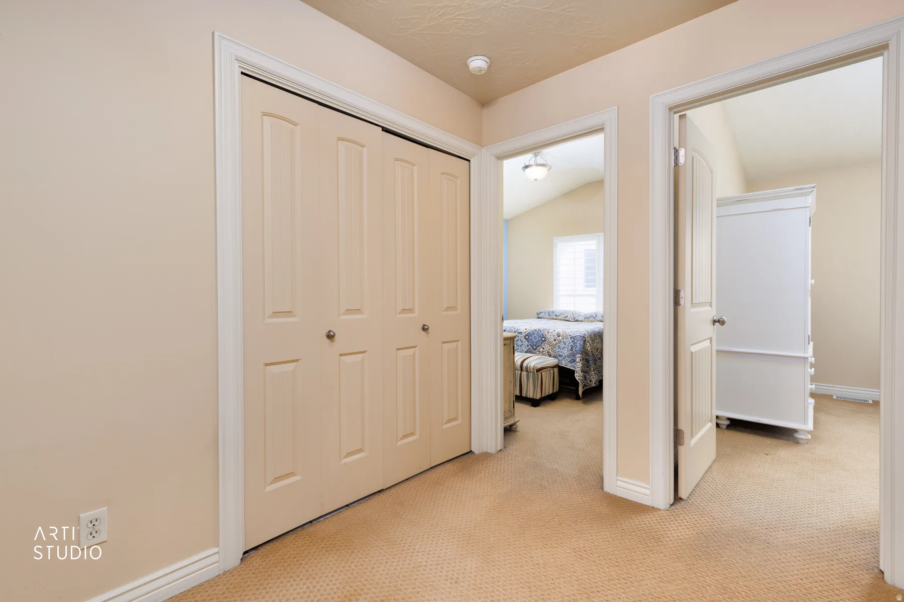 Hallway featuring neutral-toned walls, textured ceiling, and patterned carpeting