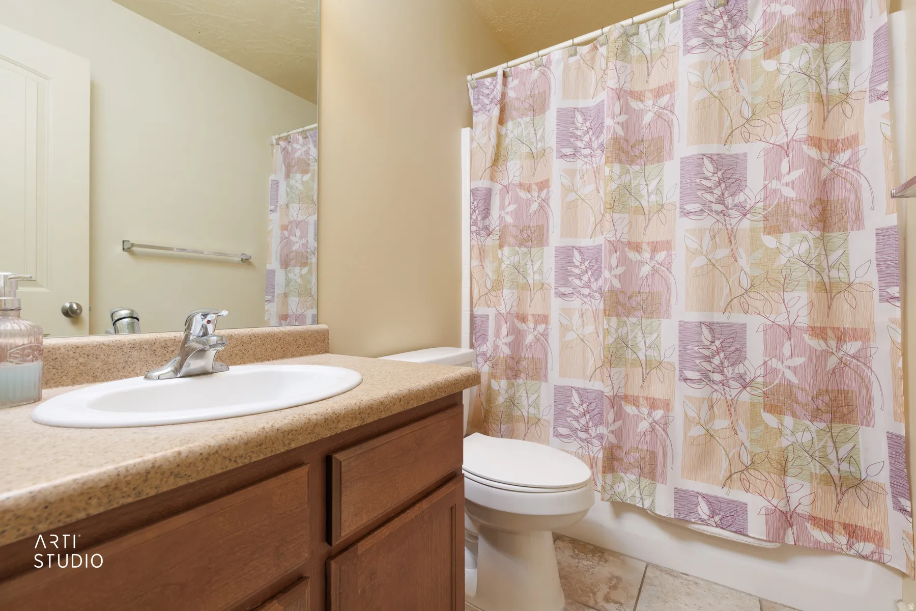 Bathroom featuring a wood-finish vanity with an integrated sink and a speckled countertop
