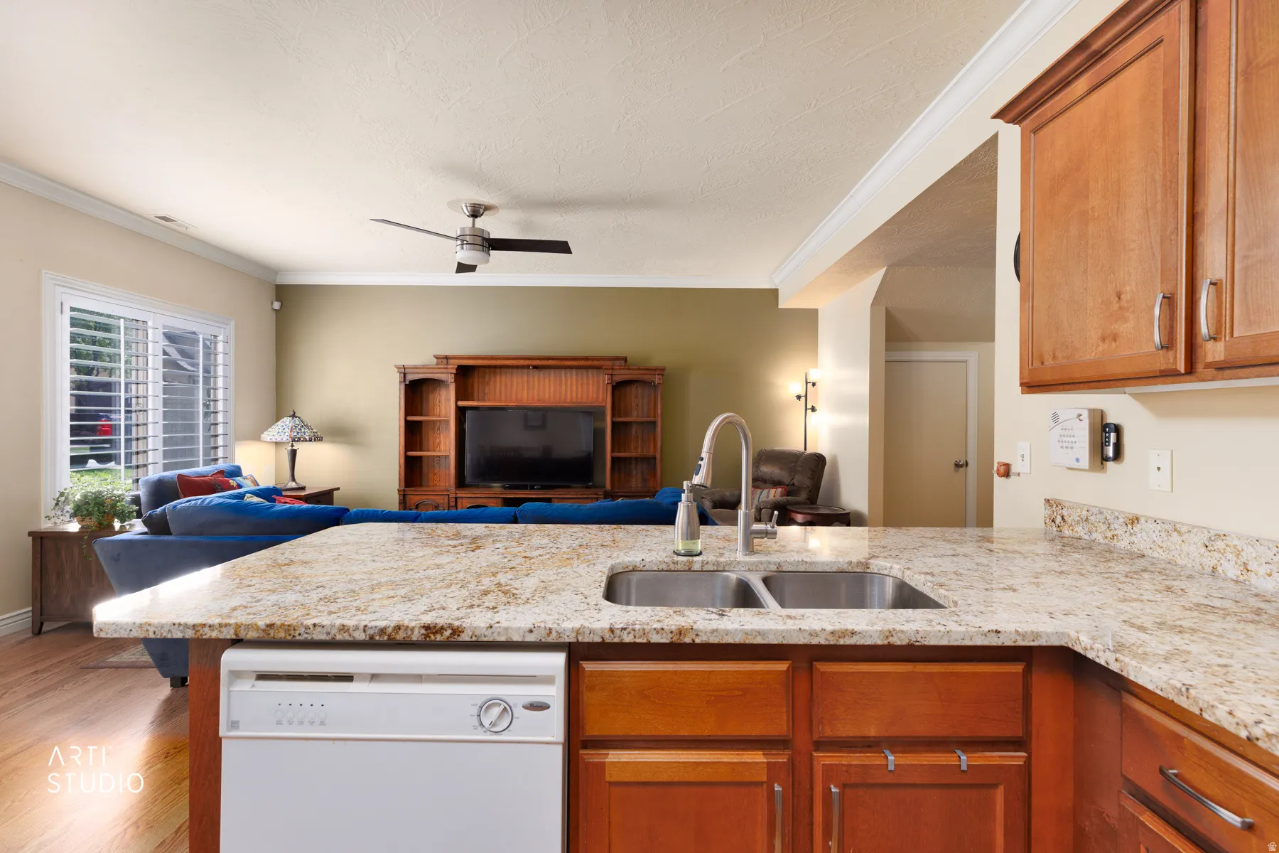 Kitchen island featuring granite countertops, a double basin stainless steel sink with a high-arc faucet, and integrated dishwasher
