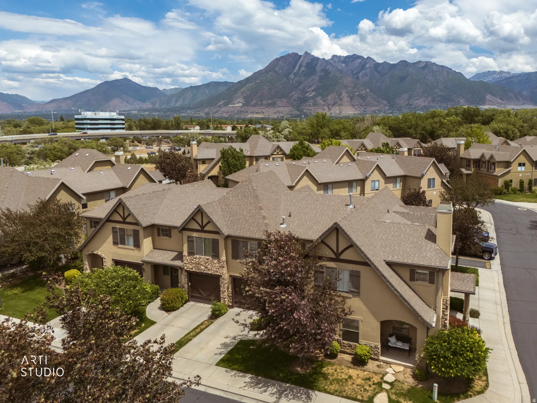 Residential community featuring multiple townhomes with earth-toned exteriors, stone accents, and gabled roofs