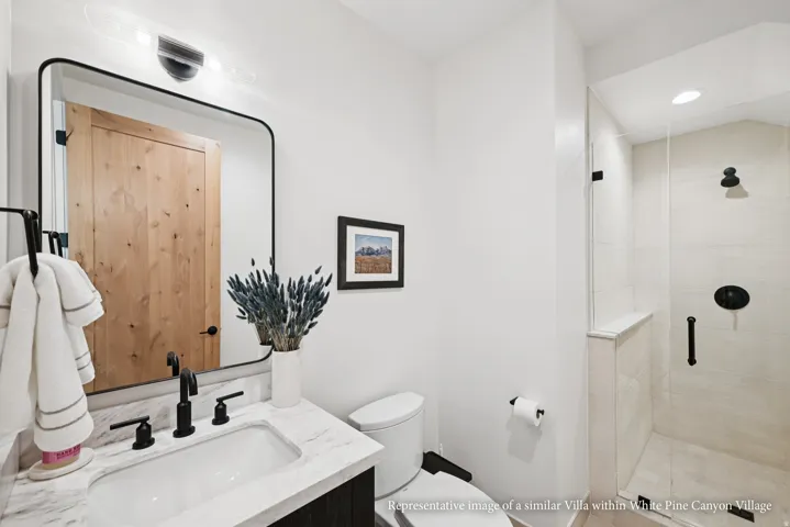 Bathroom featuring a framed mirror, a vanity with an integrated sink, a walk-in shower with a glass enclosure, and matte black fixtures