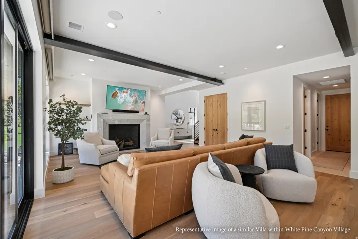 Spacious living area featuring light wood-finish flooring and a stone-clad fireplace