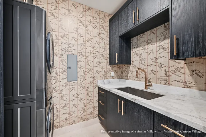 Built-in dark wood-finish cabinetry with bronze hardware, a single basin sink with a bronze faucet, and light-toned countertops
