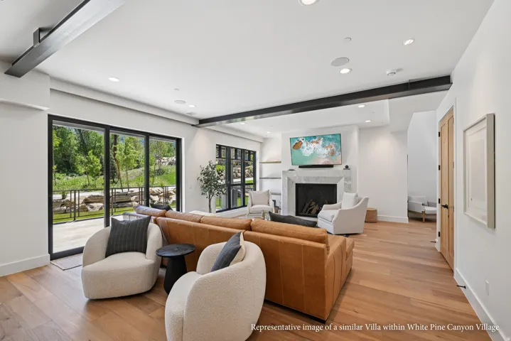 Hardwood flooring, black-framed sliding glass doors, recessed lighting, white stone fireplace surround, and exposed ceiling beams