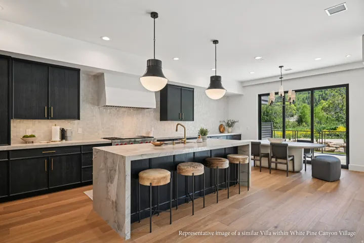 Kitchen featuring wood-finish flooring, dark cabinetry, and a large central island with a waterfall countertop