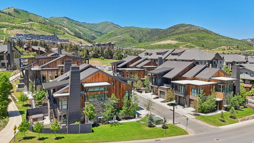 Modern architectural style with wood siding and stone accents, featuring multi-level rooflines and integrated garage access