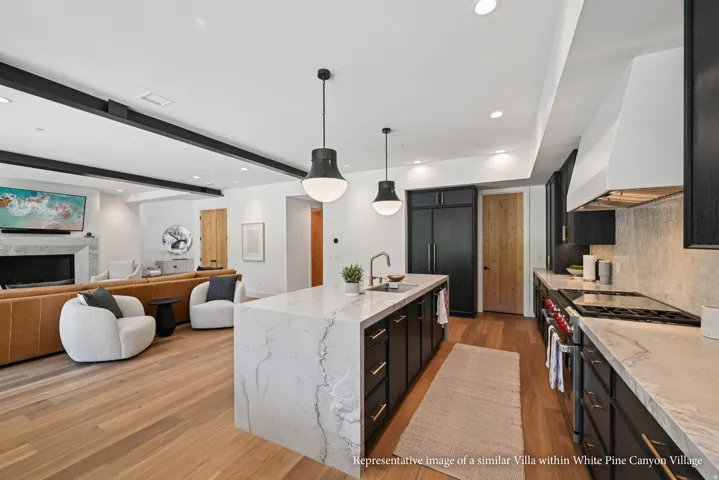 Gourmet kitchen with a waterfall island, professional-grade range, built-in refrigerator, and wood-finish flooring