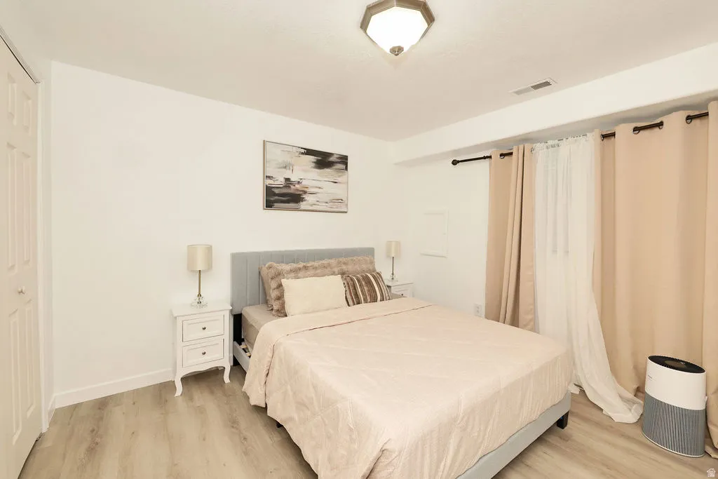 Room featuring wood-finish flooring, white walls, and a ceiling-mounted light fixture