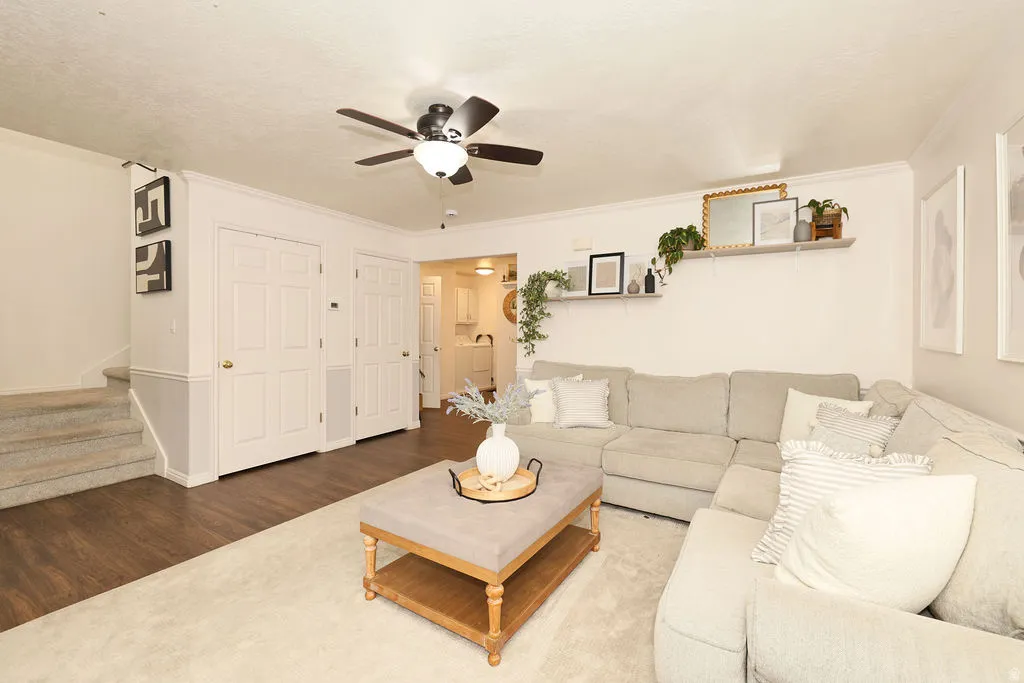 Open-concept living area with wood-finish flooring, a ceiling fan, and built-in shelving