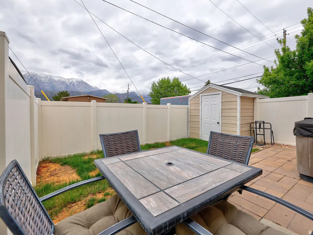 Outdoor patio space featuring paver stone flooring, a dedicated shed, and a privacy fence