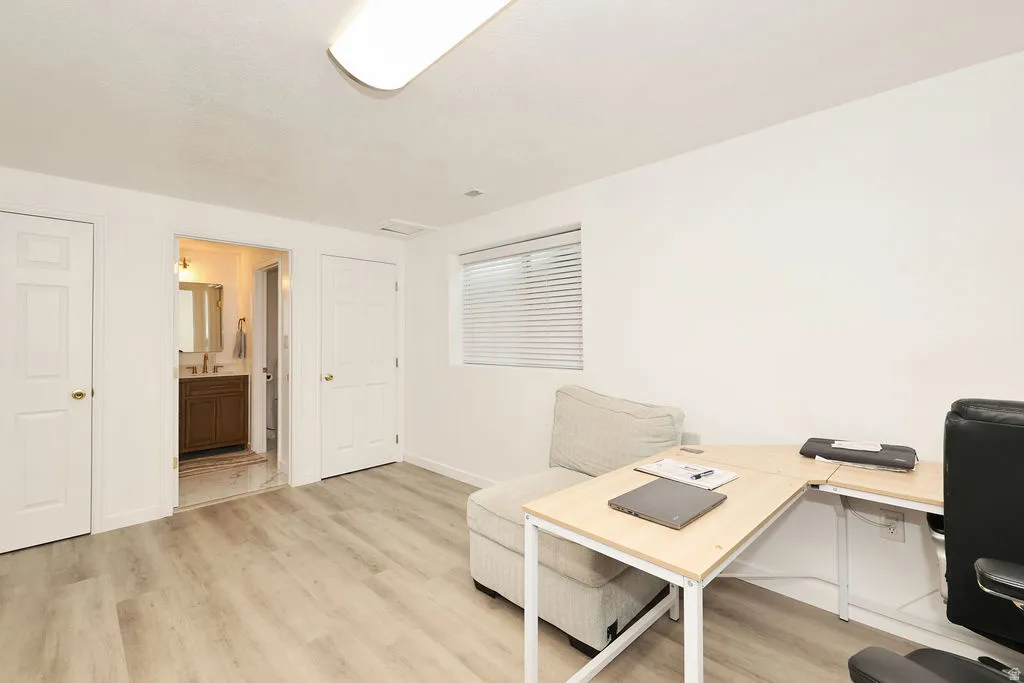 Bright room featuring light wood-finish flooring and a single window with horizontal blinds