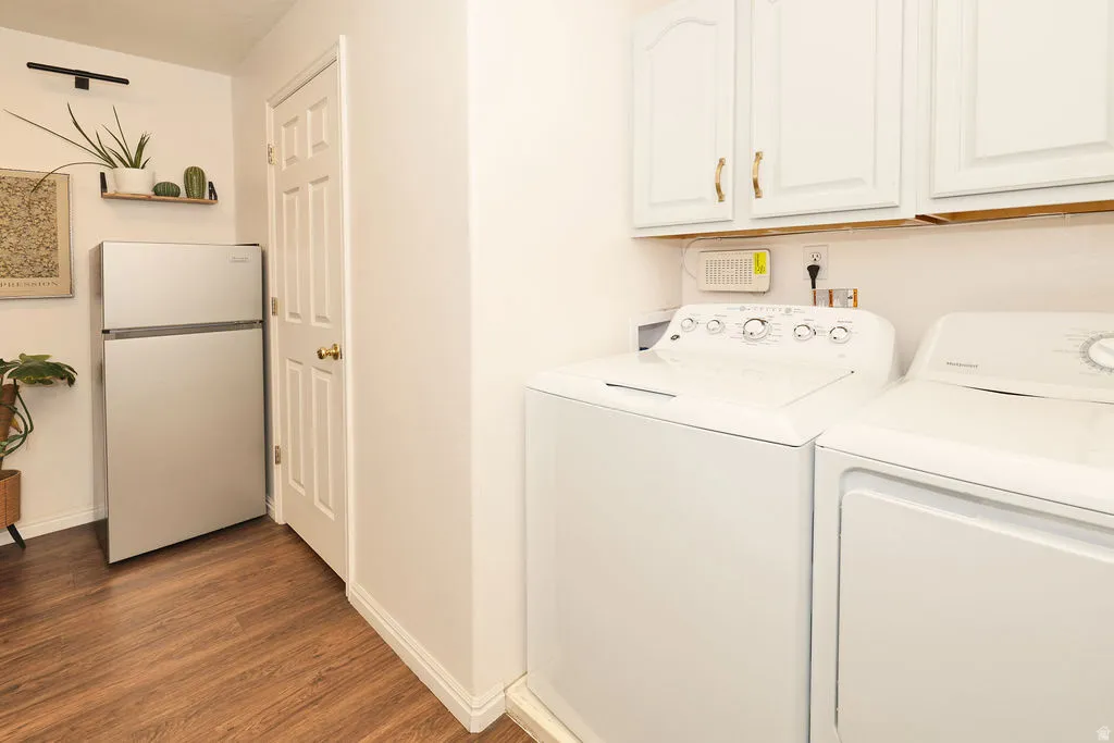 Dedicated laundry area with a washer and dryer, complemented by overhead white cabinetry with gold-tone hardware