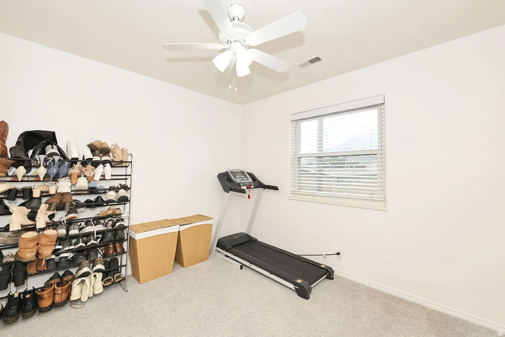 Room featuring a window with blinds, a ceiling fan, and light gray carpeting