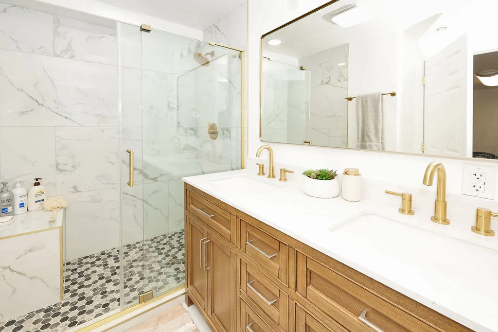 Dual vanity featuring integrated sinks, brass-finish faucets, and a wood-finish cabinet