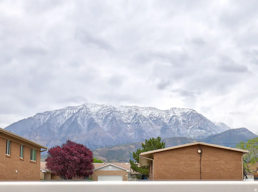 Snow-capped mountains provide a scenic backdrop to the neighborhood, featuring brick residences and mature trees