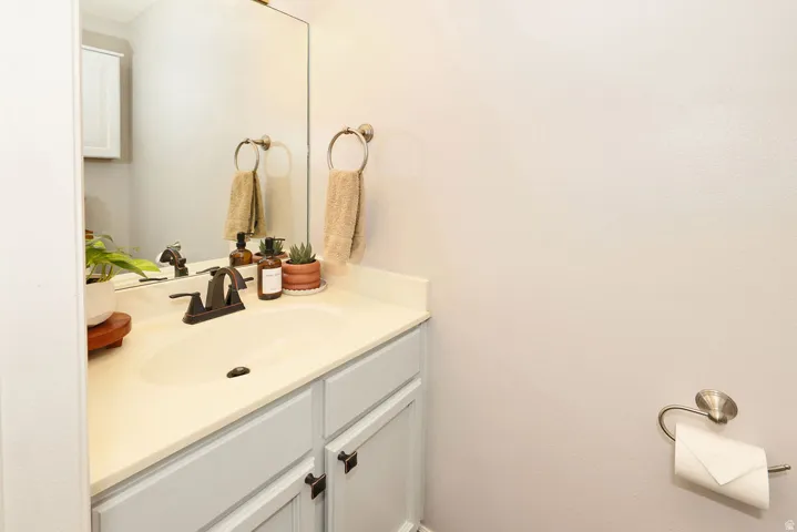 Bathroom vanity featuring a built-in sink, light-colored countertop, and painted cabinetry with dark hardware