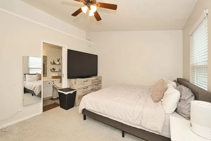 Bedroom featuring neutral wall paint, light-toned carpeting, and a ceiling fan with integrated lighting