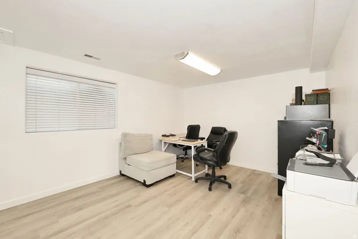 Spacious room featuring wood-finish flooring, white walls, and a recessed window with blinds