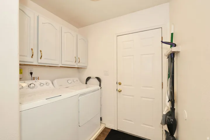 Dedicated laundry area featuring white upper cabinetry with gold-toned hardware, providing storage