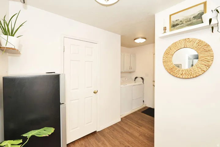 Laundry area featuring a top-load washer and dryer, white cabinetry, and wood-finish flooring