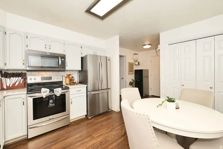 Kitchen featuring stainless steel appliances, white cabinetry, subway tile backsplash, and wood-finish flooring