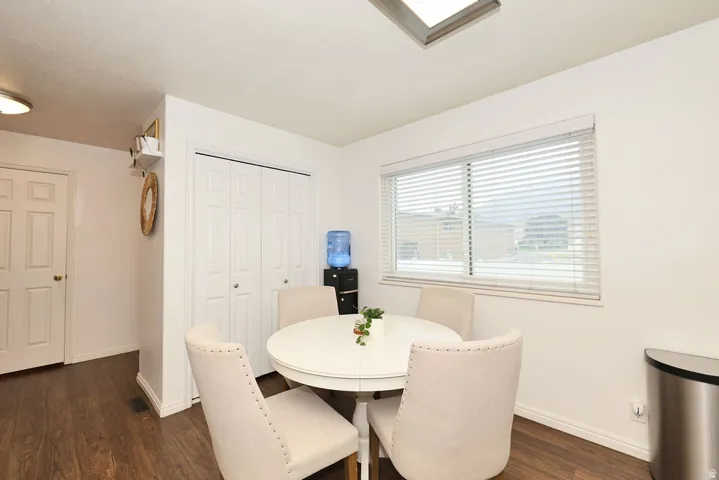 Dining area with wood-finish flooring, a large window with horizontal blinds, built-in bi-fold closet doors, and recessed ceiling lighting