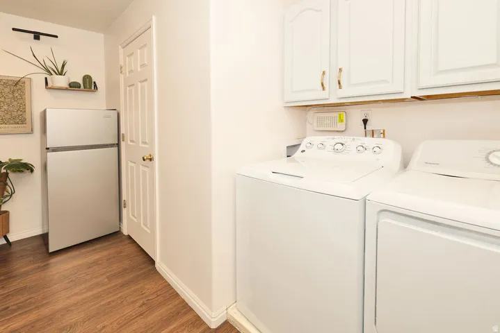 Dedicated laundry area with a washer and dryer, complemented by overhead white cabinetry with gold-tone hardware