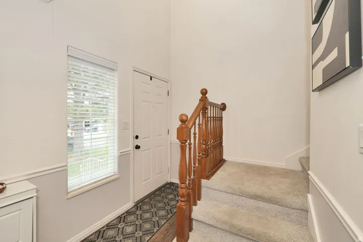 Entryway featuring a two-tone wall treatment, a window with horizontal blinds, and a white paneled door