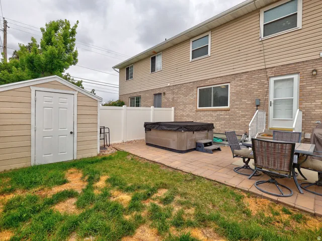 Backyard featuring a paver patio, a hot tub with cover, and a storage shed