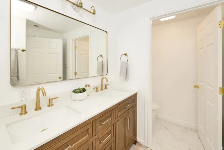 Bathroom featuring a double vanity with wood-finish cabinetry, white countertops, and dual integrated sinks