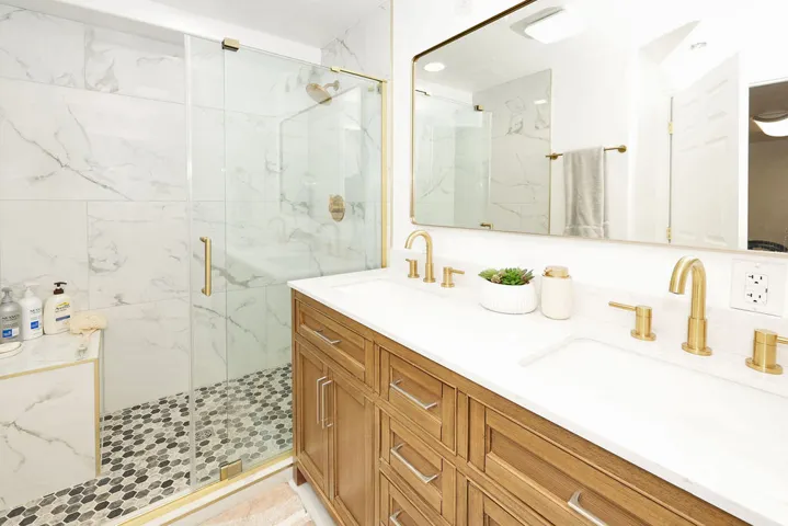Dual vanity featuring integrated sinks, brass-finish faucets, and a wood-finish cabinet