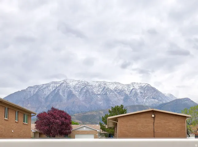 Snow-capped mountains provide a scenic backdrop to the neighborhood, featuring brick residences and mature trees